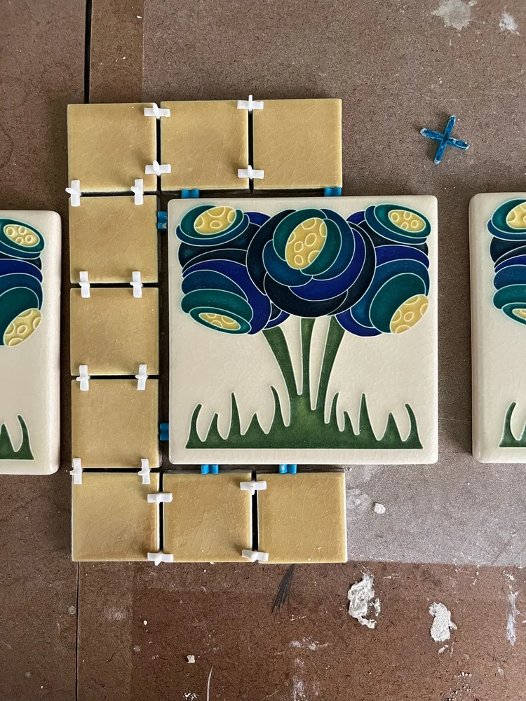 Hand-glazed art nouveau flower tiles being laid out with spacers