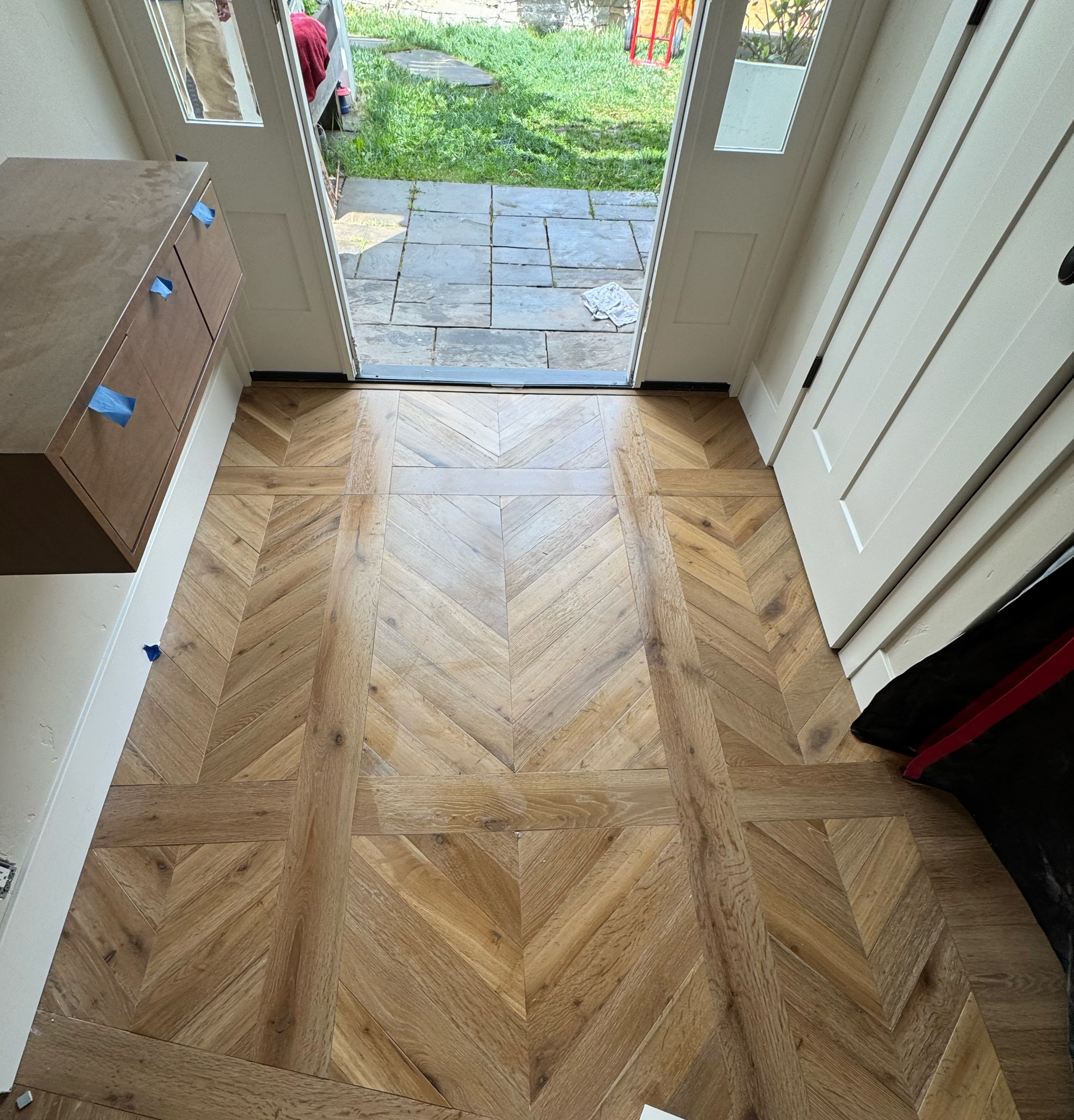 Chevron parquet white oak floor at an entry with wide plank rail borders