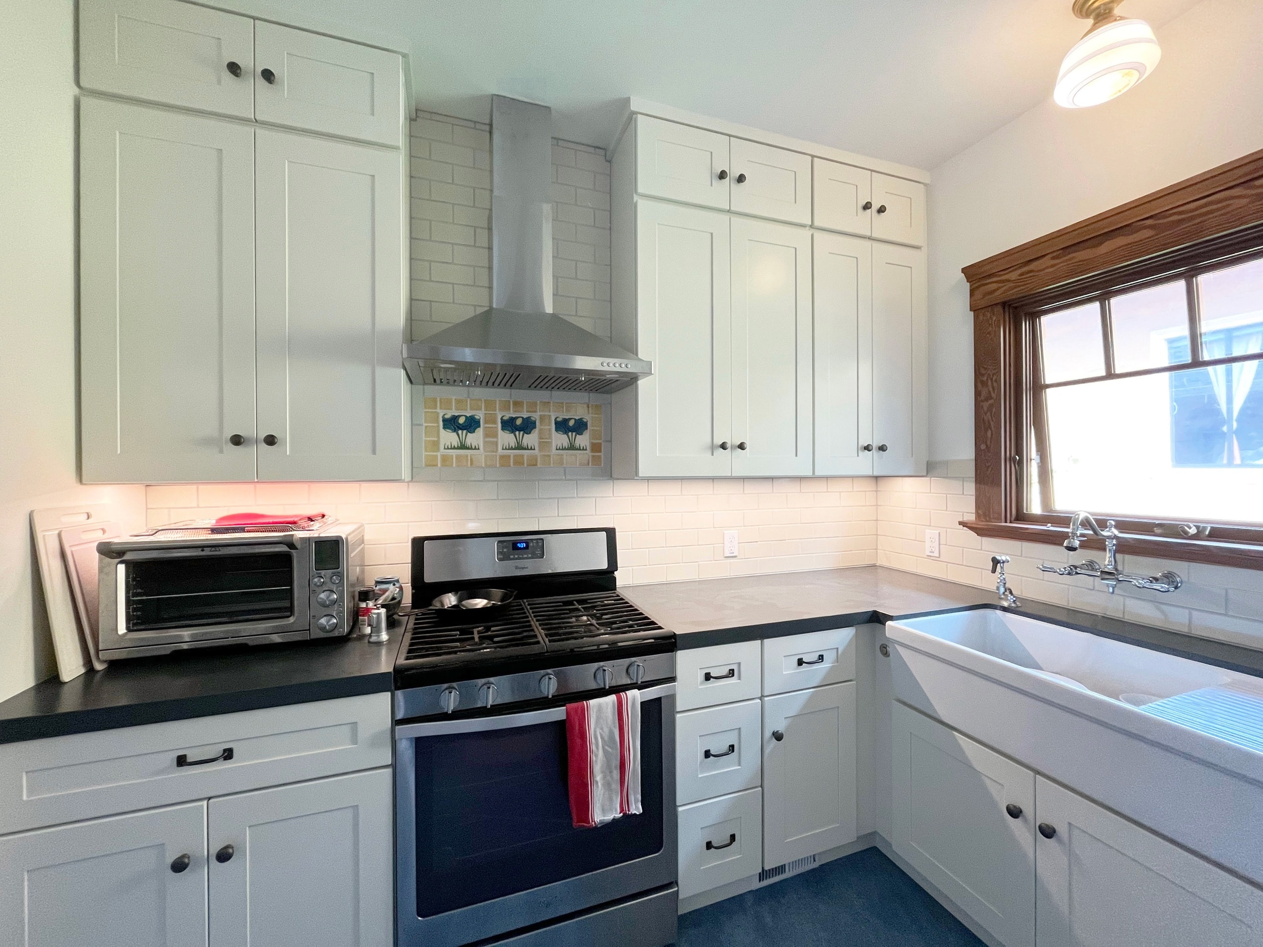 White shaker kitchen with subway tile backsplash and art tile inlay above the range